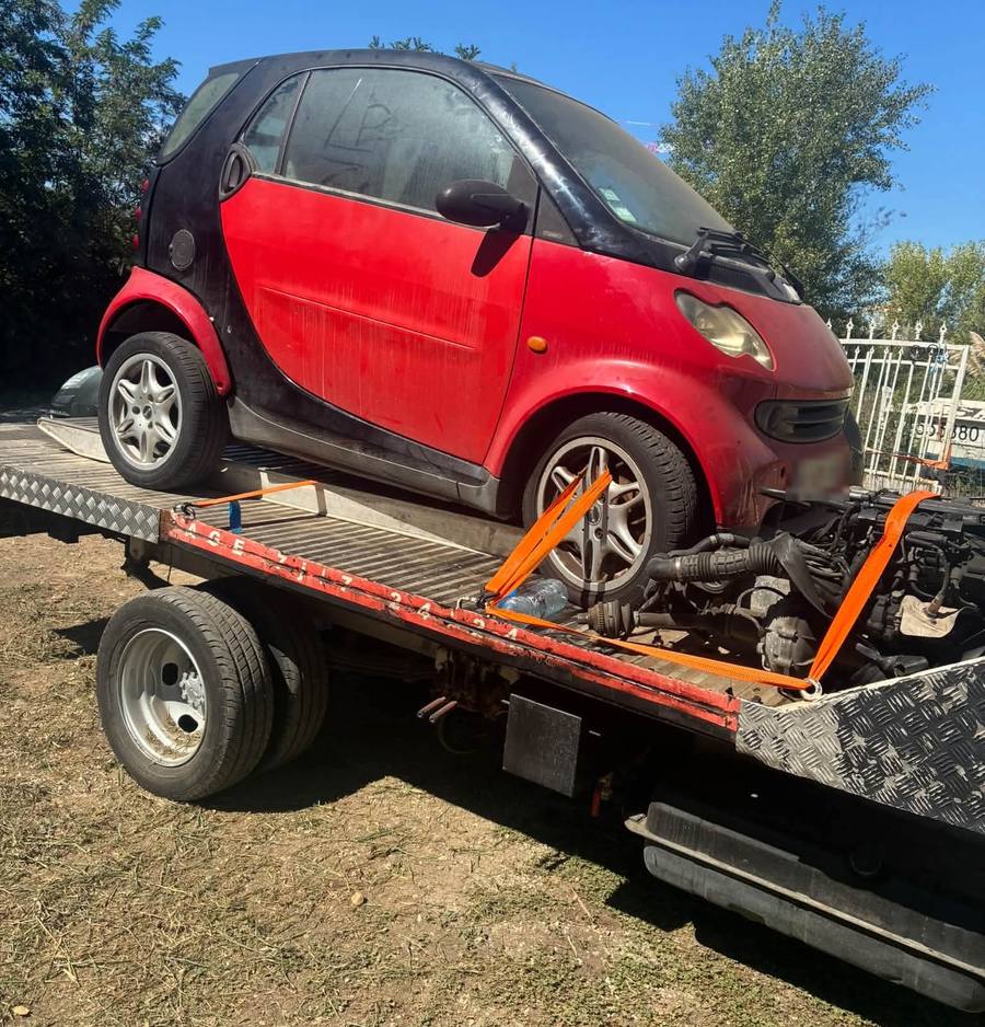 Une Smart rouge et noire sanglée sur le plateau avec un moteur